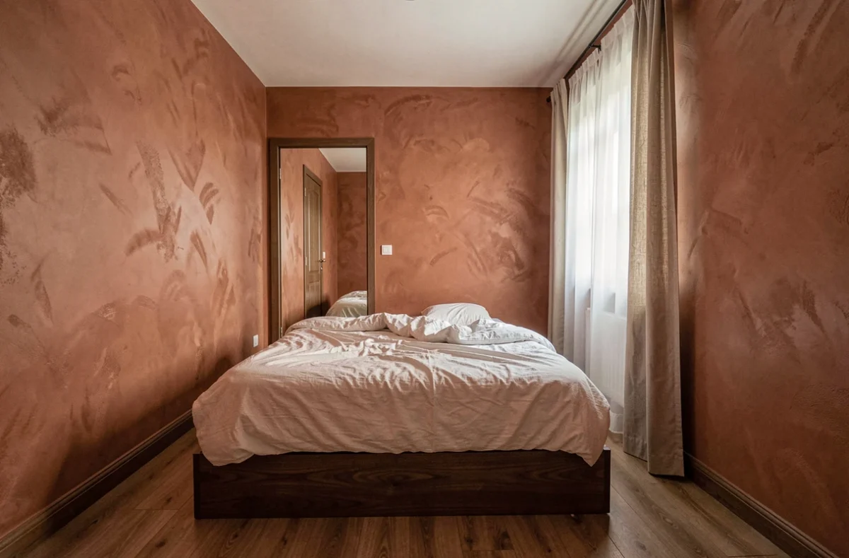 Petite chambre d'appartement avec lit aligné face à la porte fermée, vue d'ensemble de la pièce