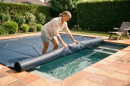 Femme installant une bâche de protection sur une piscine extérieure en été dans un jardin suburban