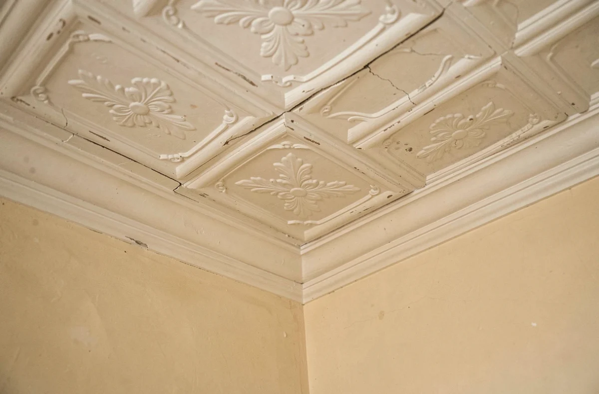 Détail de dalles décoratives posées au plafond d'un appartement ancien pour camoufler des fissures et imperfections