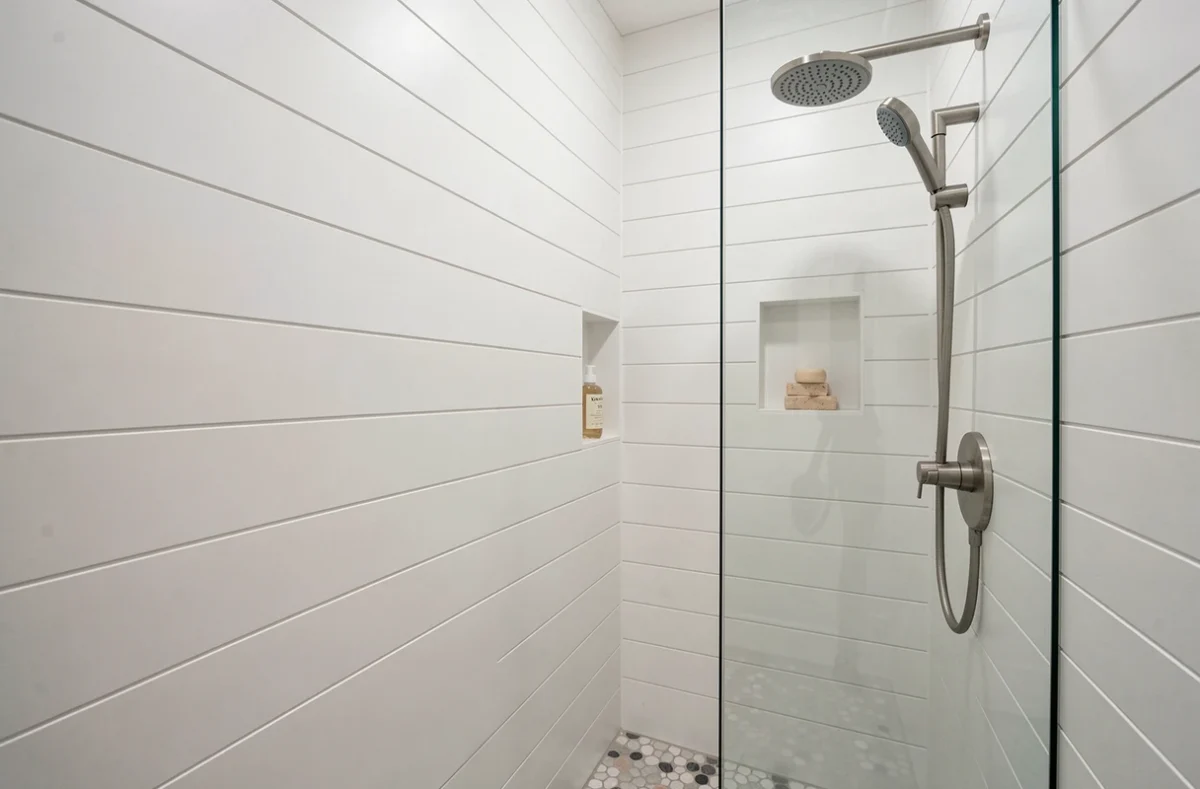 Salle de bain moderne avec panneaux muraux PVC blancs installés autour d'une douche à l'italienne pour protéger les murs
