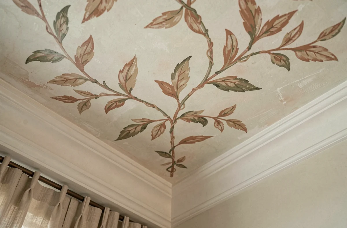 Détail d'un plafond peint à la main motif botanique fresque terracotta dans un hôtel boutique tendance 2026