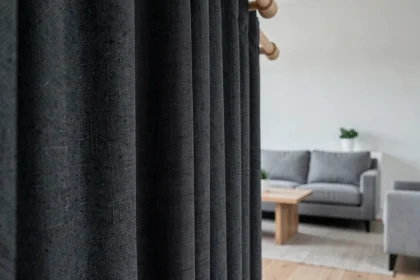 Rideau occultant en tissu épais gris anthracite sur une tringle en bois dans un salon minimaliste scandinave