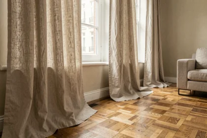 Rideaux en lin tombant jusqu'au sol dans un salon minimaliste avec parquet en bois et mur beige