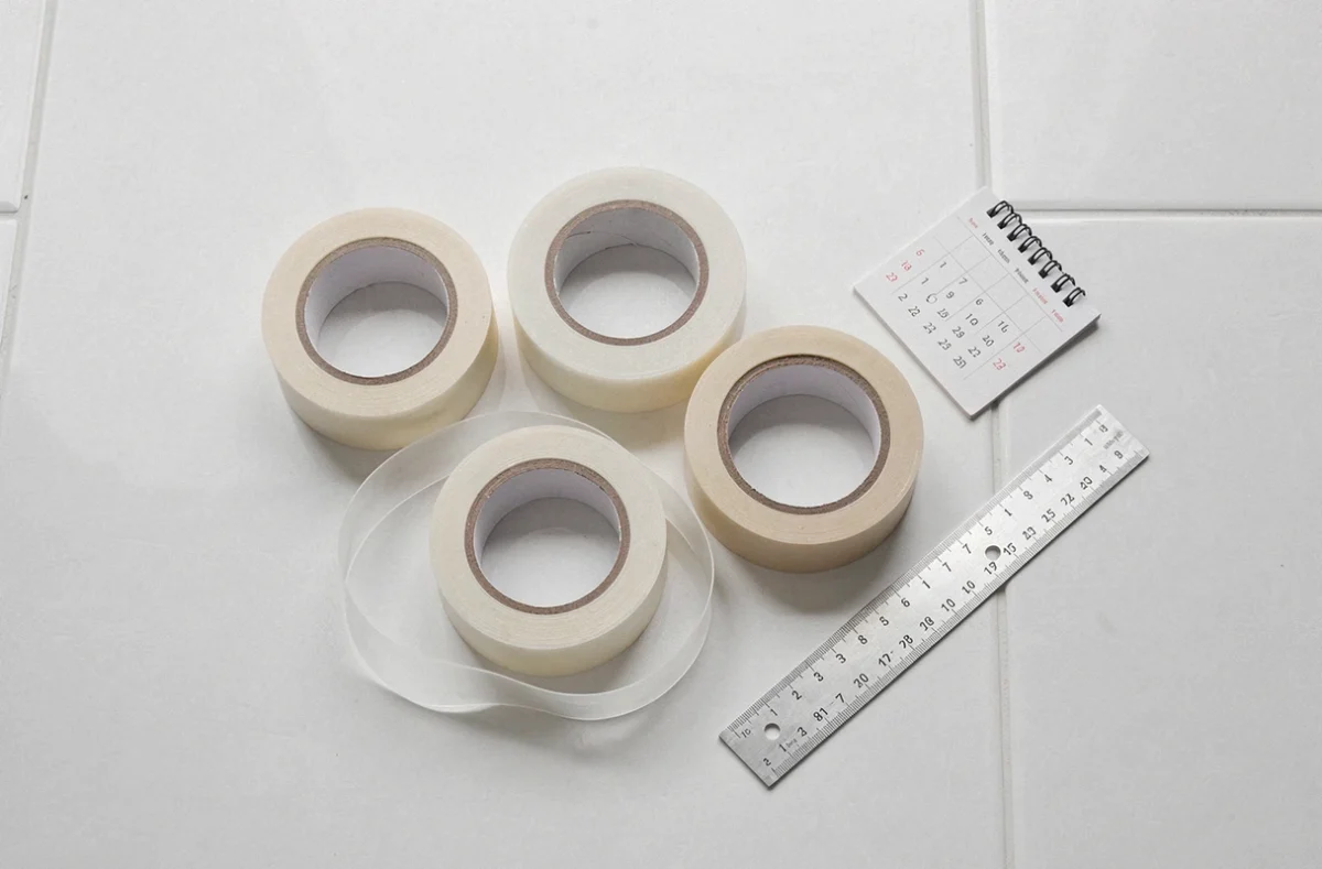 Rouleaux de ruban adhésif transparent et de masquage disposés sur une surface blanche avec un calendrier