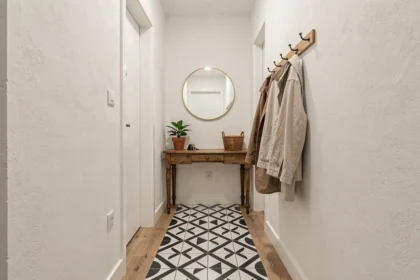Entrée moderne rénovée avec console en bois, miroir laiton et carrelage géométrique noir et blanc